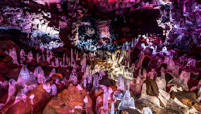 Crystals inside Raufarhólshellir Lava Cave, Iceland, illuminated with colorful lights.