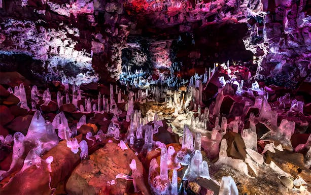 Crystals inside Raufarhólshellir Lava Cave, Iceland, illuminated with colorful lights.