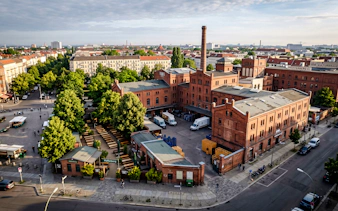 Aerial view of Pfefferberg complex in Berlin, featuring historic red brick buildings and a courtyard.