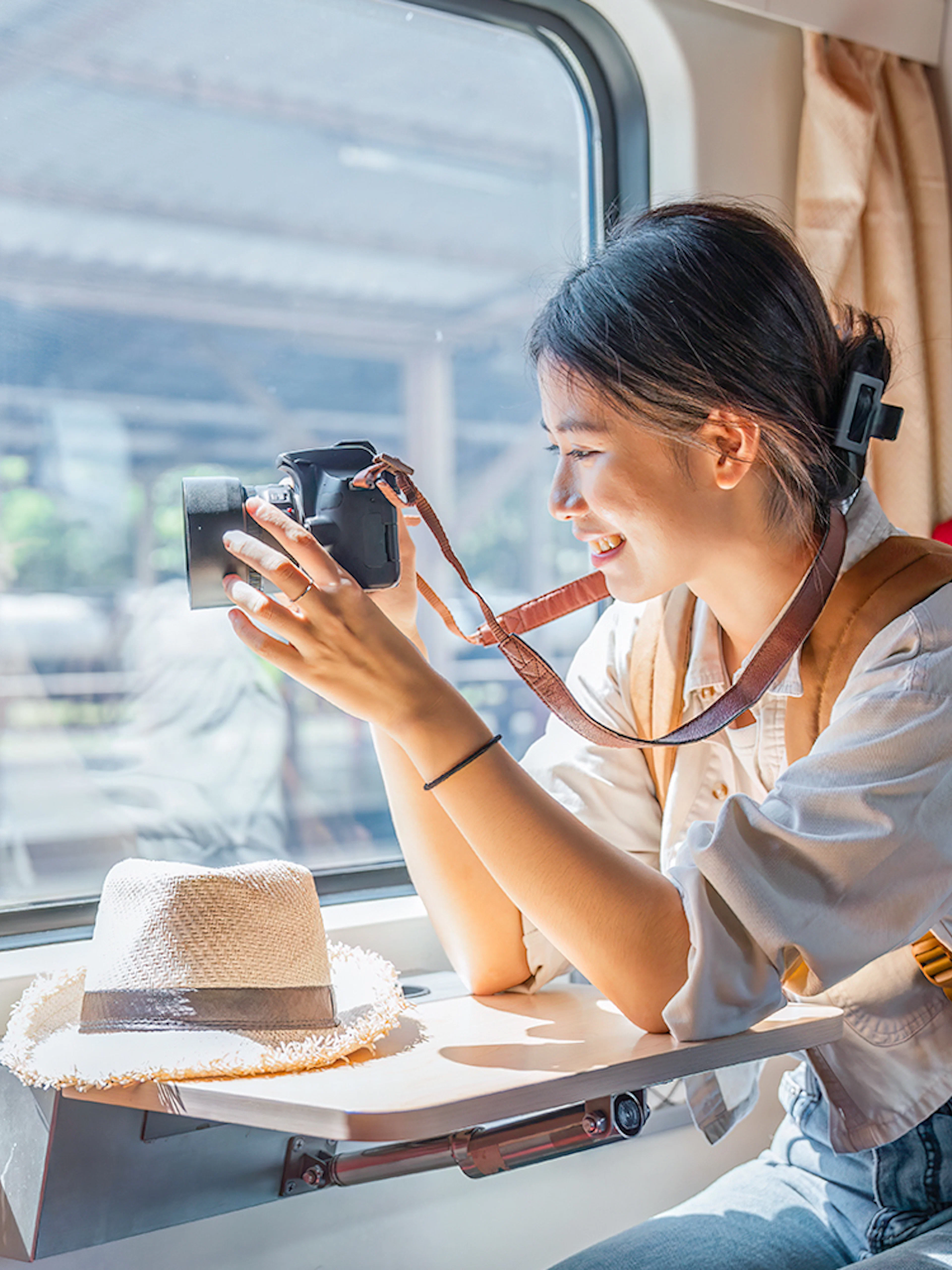 Asian female tourist taking photos from train window with camera.