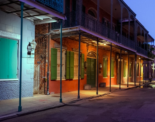 French Quarter New Orleans street scene at night with illuminated historic buildings and lively atmosphere.