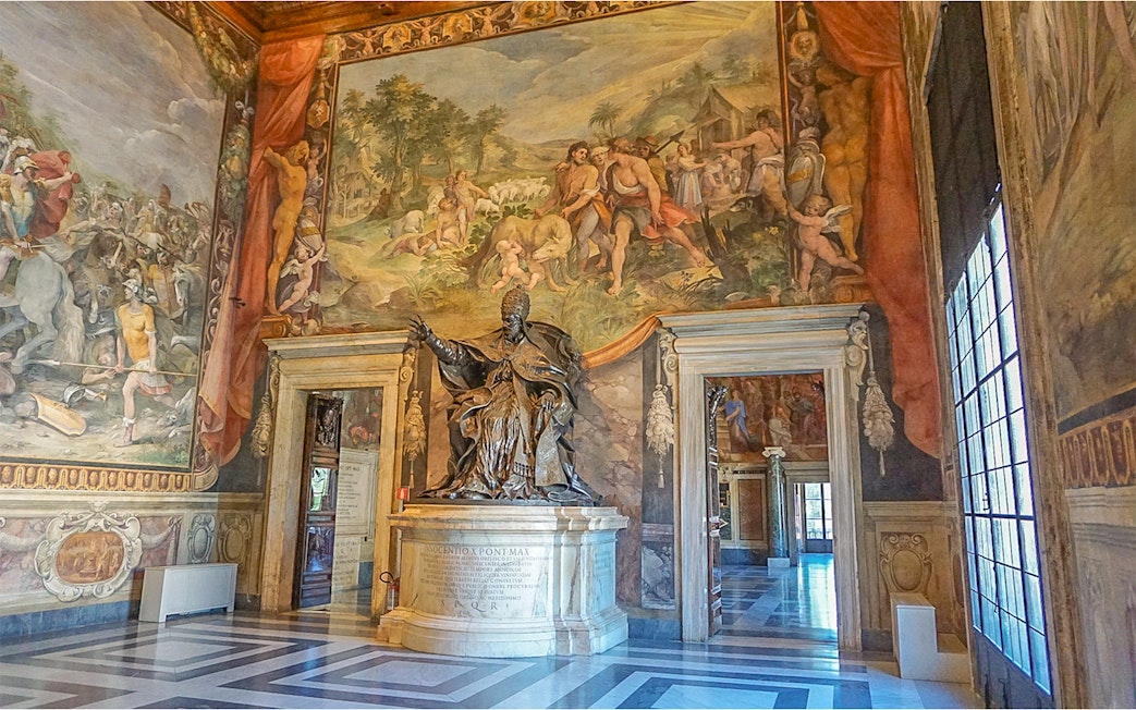 Capitoline Museums interior with statue and frescoes during guided tour in Rome.