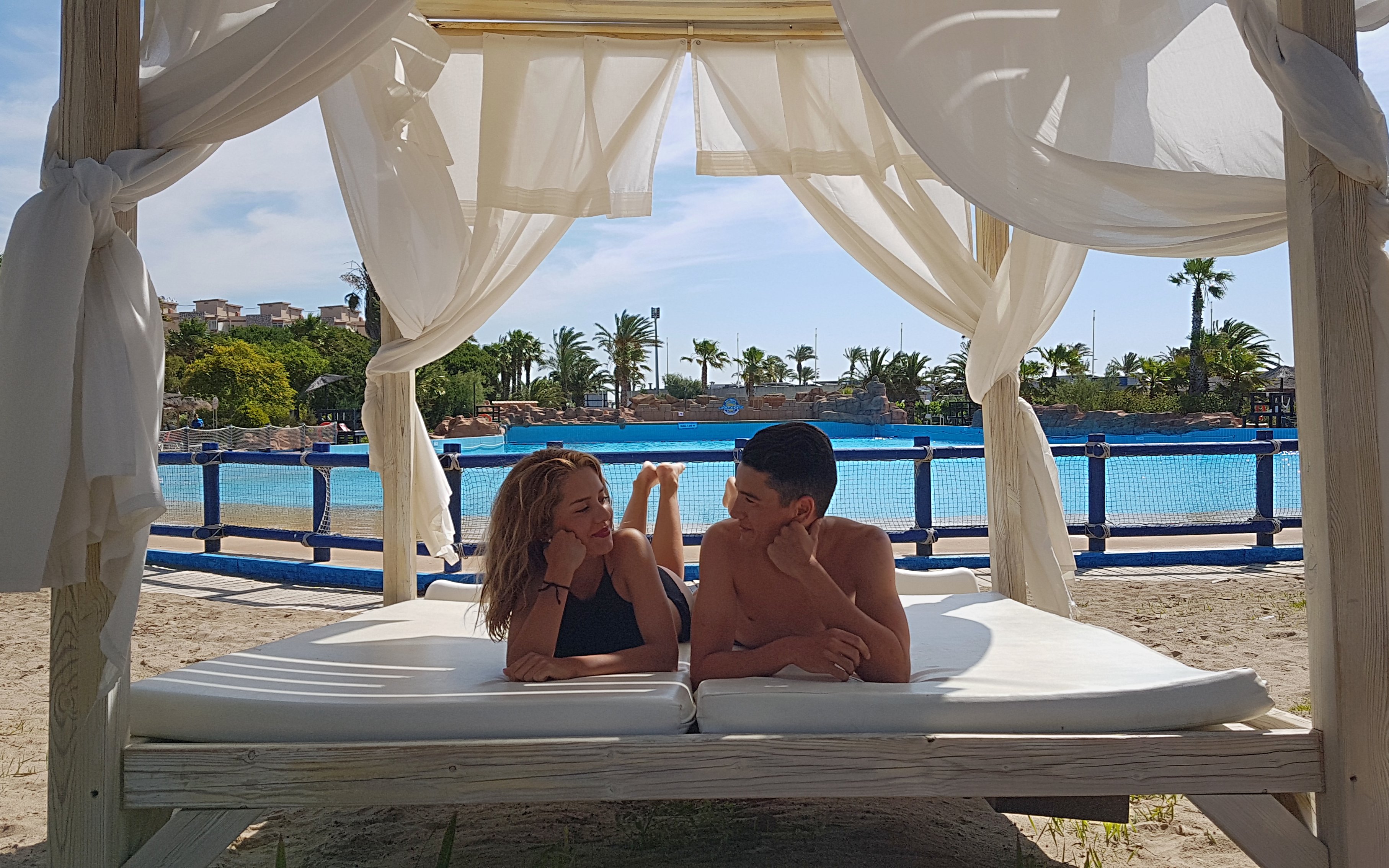 Couple relaxing on a cabana by the pool at Aquopolis Costa Daurada, Tarragona.