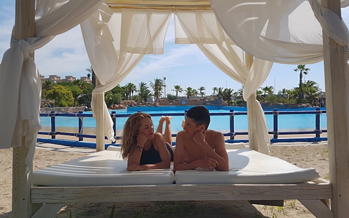 Couple relaxing on a cabana by the pool at Aquopolis Costa Daurada, Tarragona.