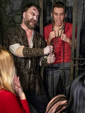 Actor in medieval costume interacting with visitors at Hamburg Dungeon.