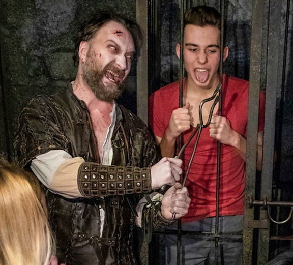 Actor in medieval costume interacting with visitors at Hamburg Dungeon.