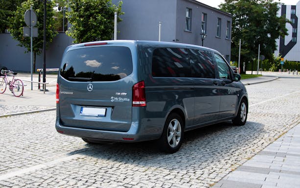 Krakow airport transfer van parked on cobblestone street.