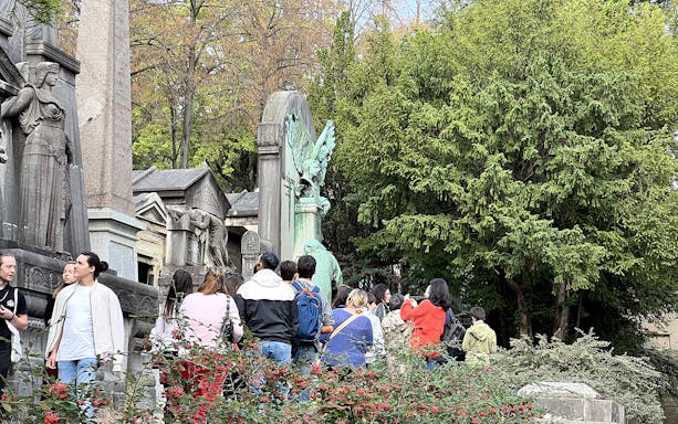 Tour group exploring statues and tombs at Père Lachaise Cemetery in Paris.