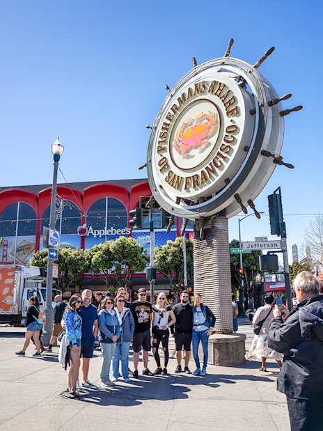 Guide photographing tourists at Fisherman's Wharf Crab sign, San Francisco.
