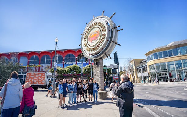 Guide photographing guests at Fisherman's Wharf Crab sign in San Francisco.