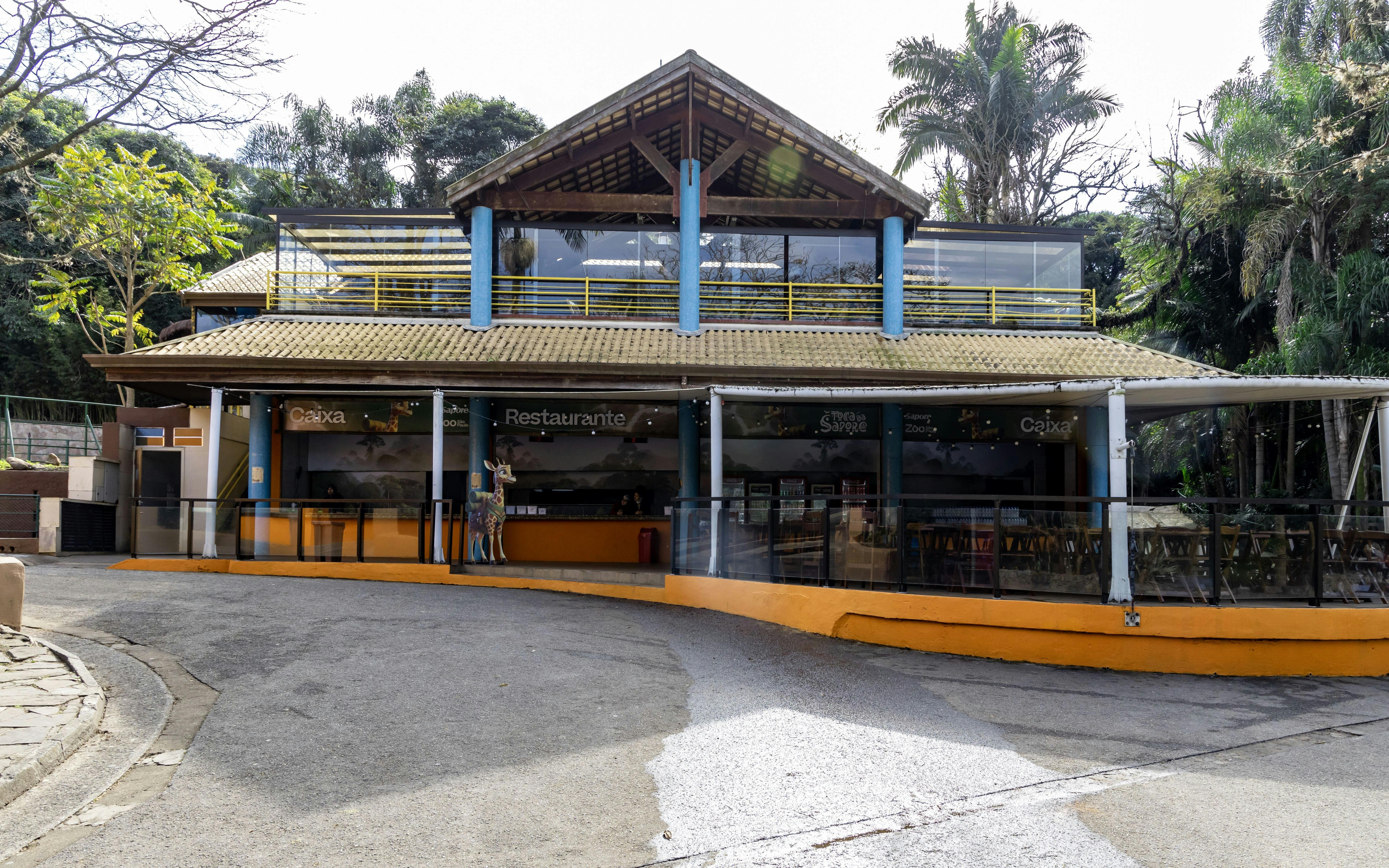 Restaurant entrance at São Paulo Zoo with outdoor seating and tropical surroundings.