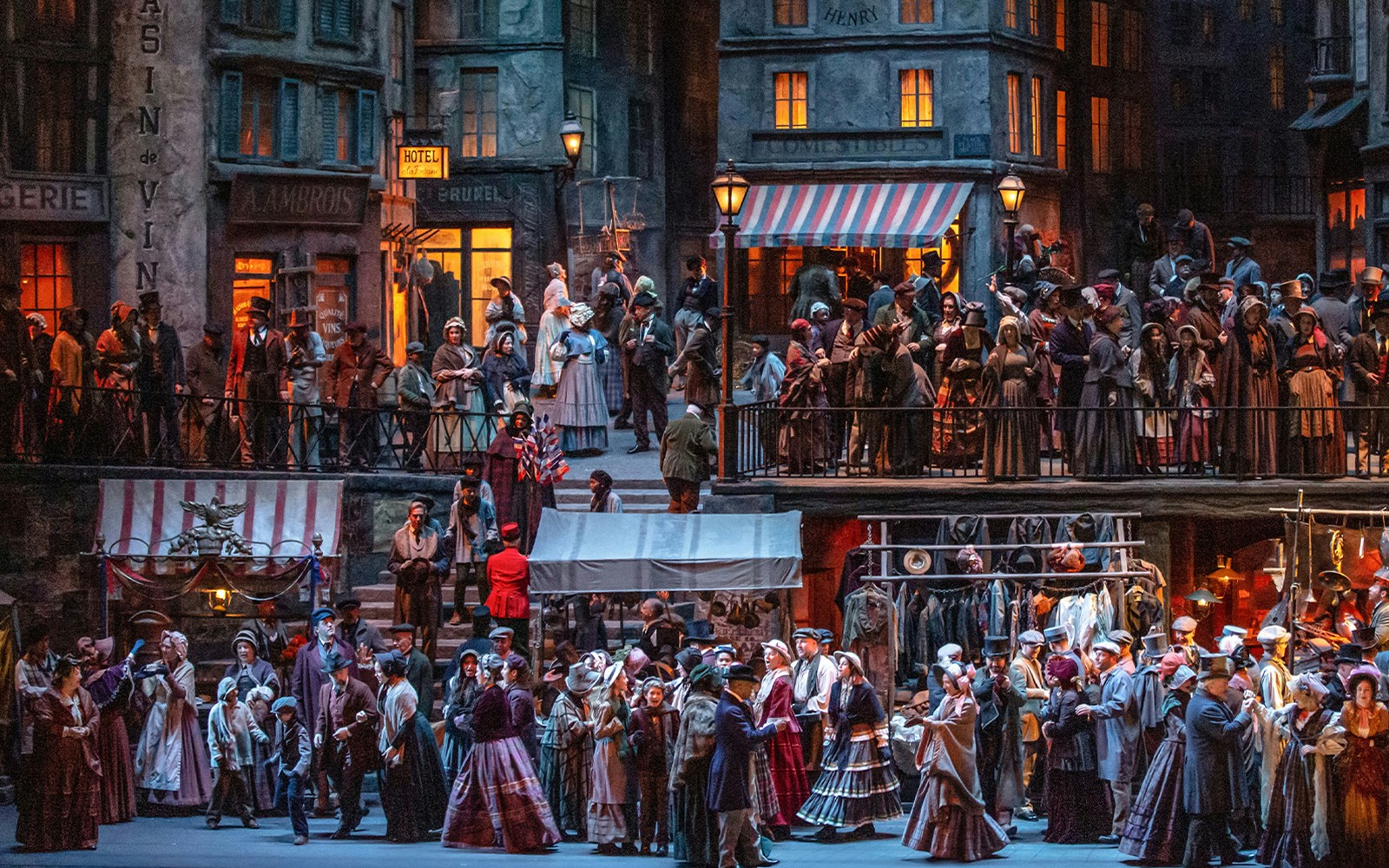 Crowded Parisian street scene from La Boheme opera with people in period costumes.
