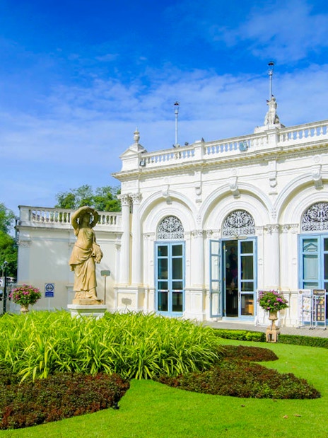 Ayutthaya's Bang Pa-In Palace garden with statue and ornate building.