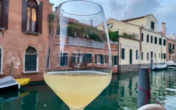 Wine glass by a canal in Venice during a guided food tour.