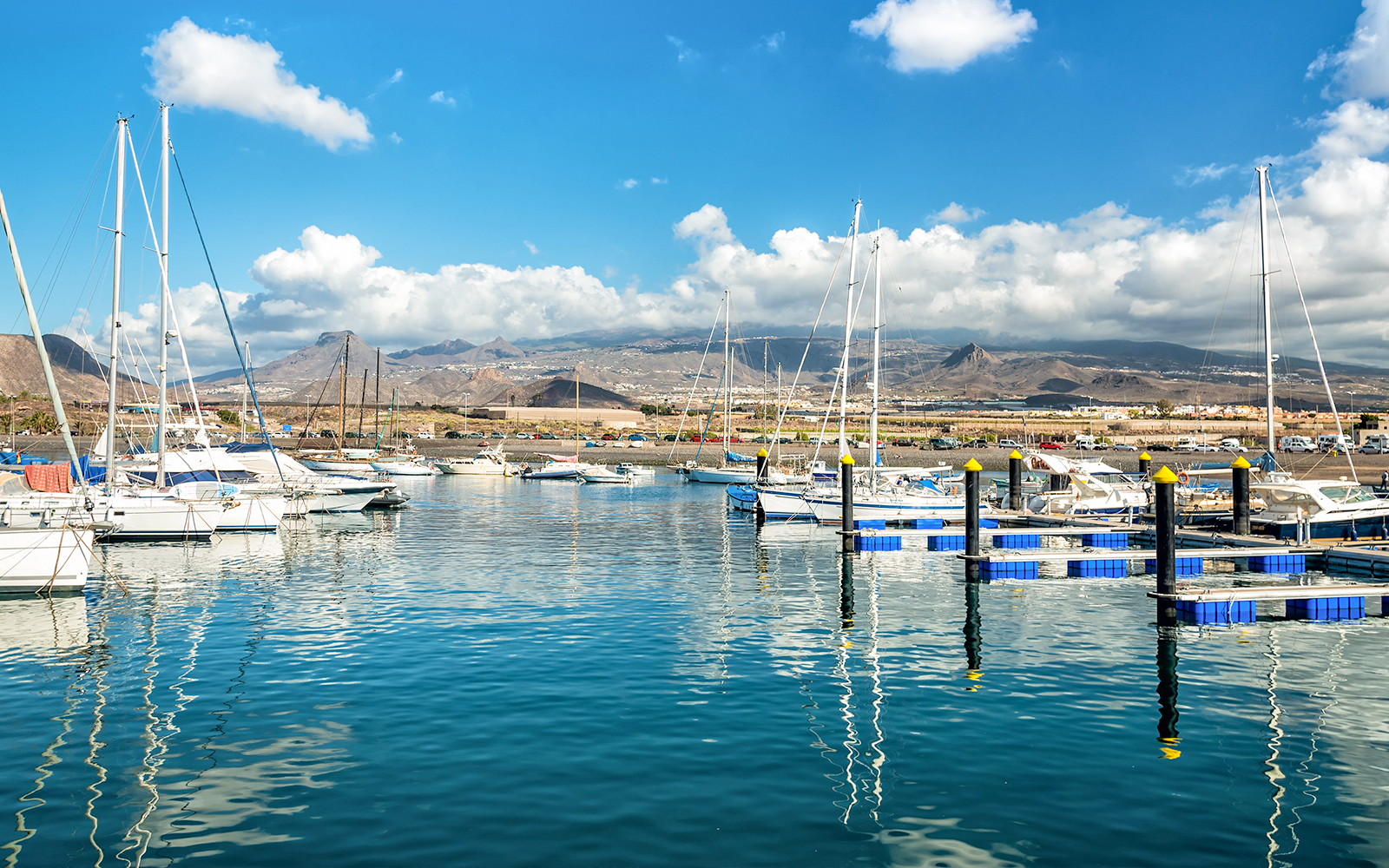 Las Galletas marina with sailboats and mountains in Tenerife under a sunny sky.
