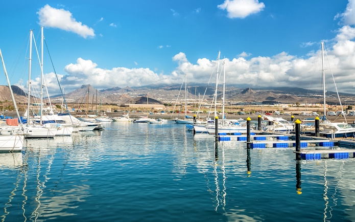 Las Galletas marina with sailboats and mountains in Tenerife under a sunny sky.