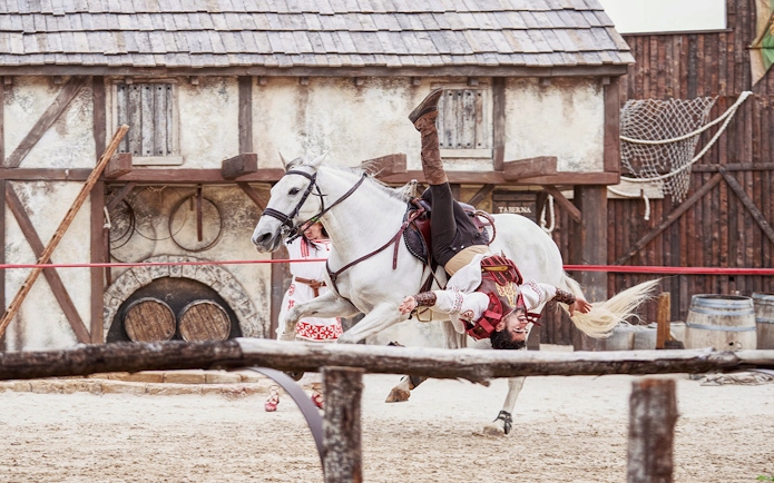Performer in costume doing acrobatics on a white horse at Puy du Fou España.