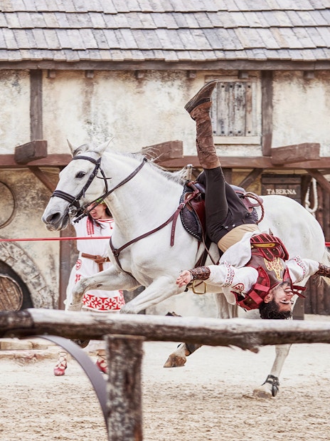 Performer in costume doing acrobatics on a white horse at Puy du Fou España.
