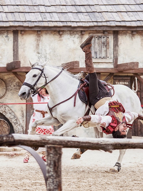 Performer in costume doing acrobatics on a white horse at Puy du Fou España.