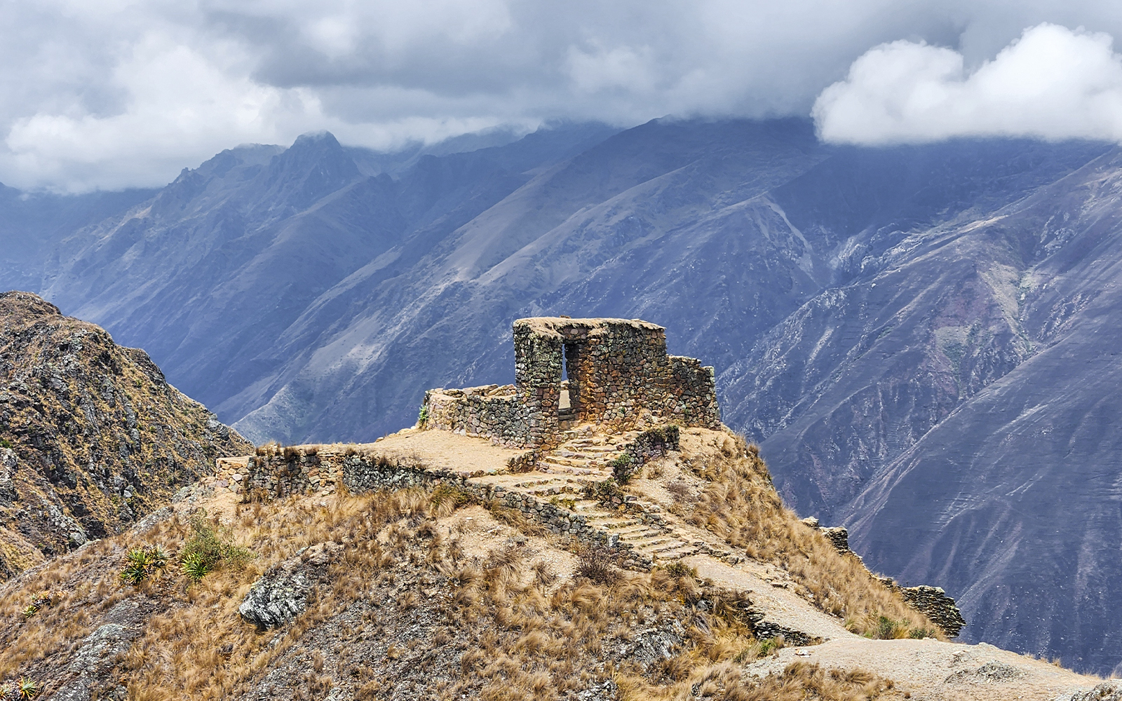 Stone structure at Sun Gate with panoramic mountain view in Peru.