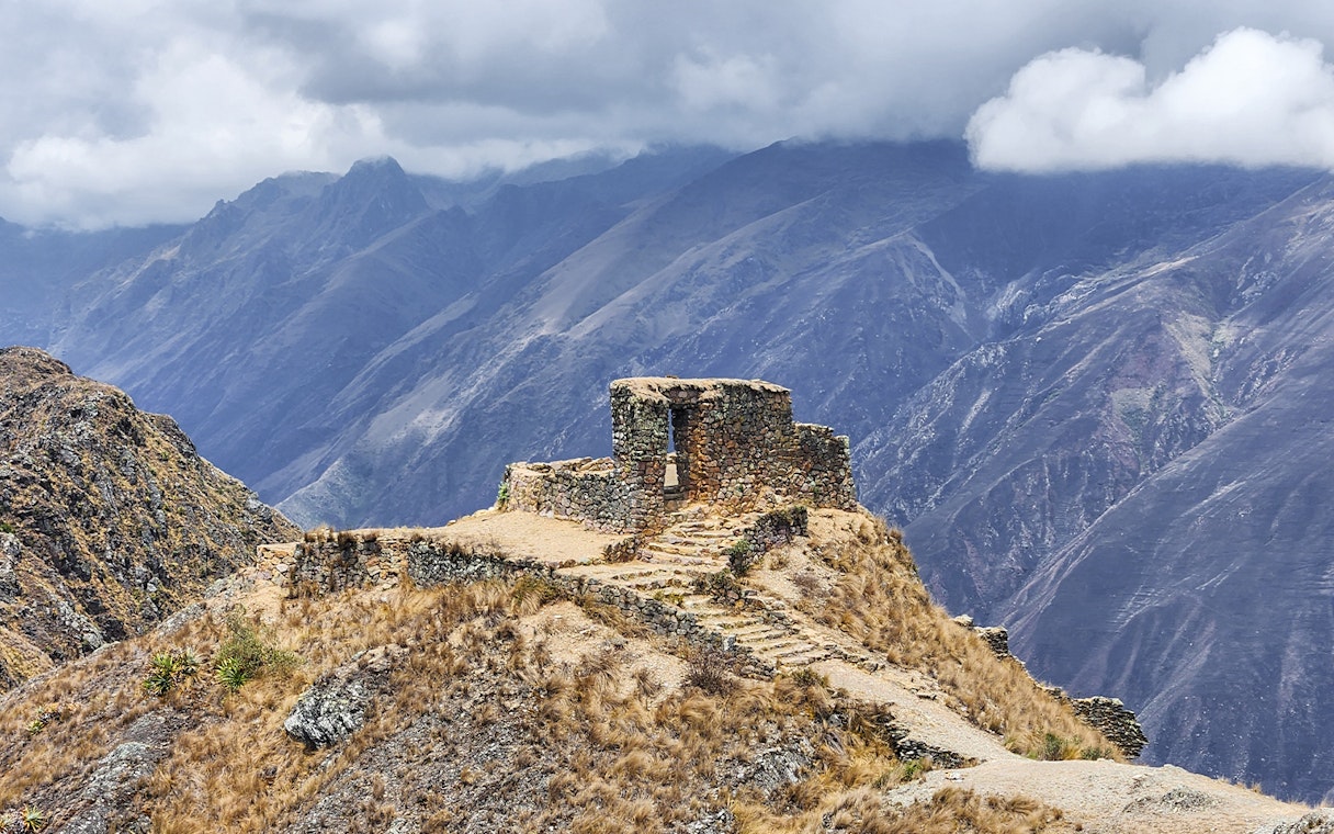 Stone structure at Sun Gate with panoramic mountain view in Peru.