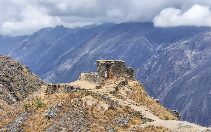 Stone structure at Sun Gate with panoramic mountain view in Peru.