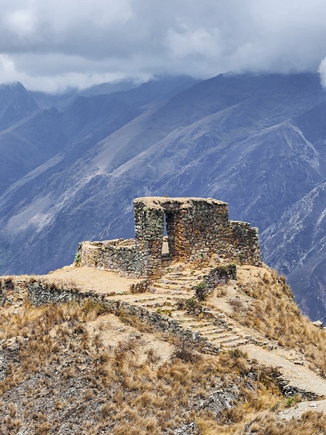 Stone structure at Sun Gate with panoramic mountain view in Peru.