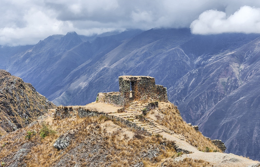 Stone structure at Sun Gate with panoramic mountain view in Peru.