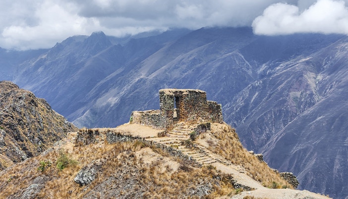 Stone structure at Sun Gate with panoramic mountain view in Peru.