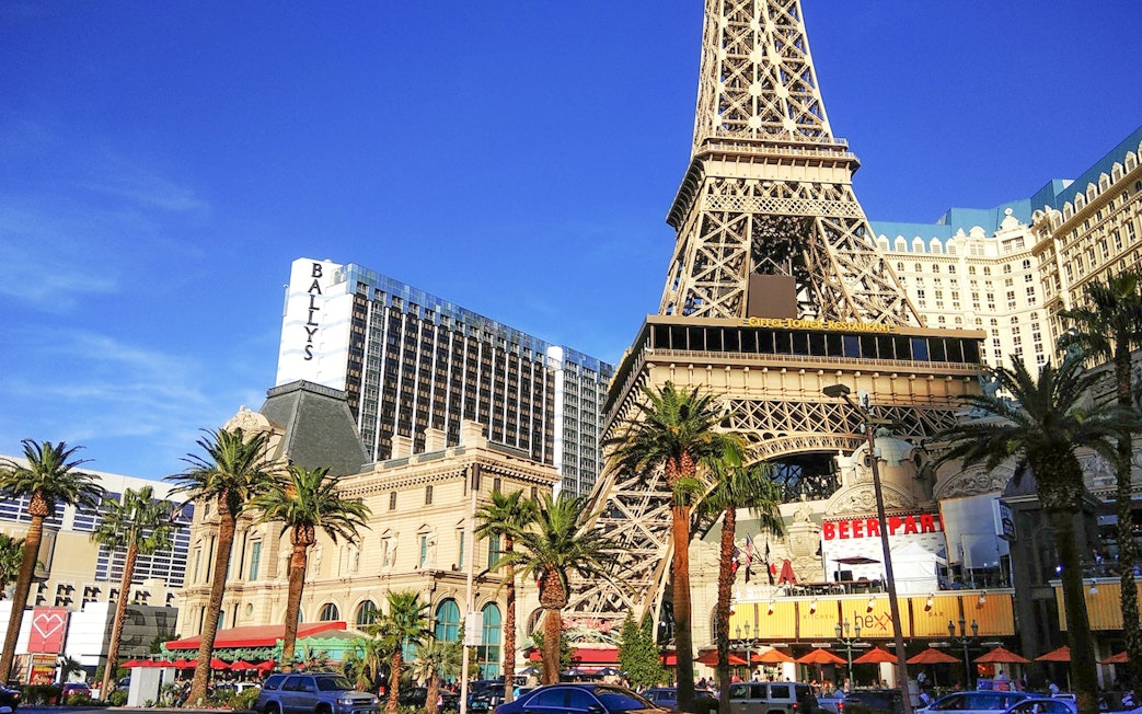 Eiffel Tower replica in Las Vegas with nearby hotels and palm trees.