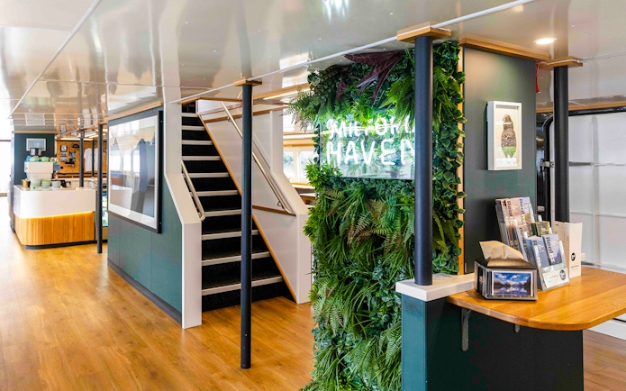 Interior of Milford Sound Haven ship with greenery wall and staircase.