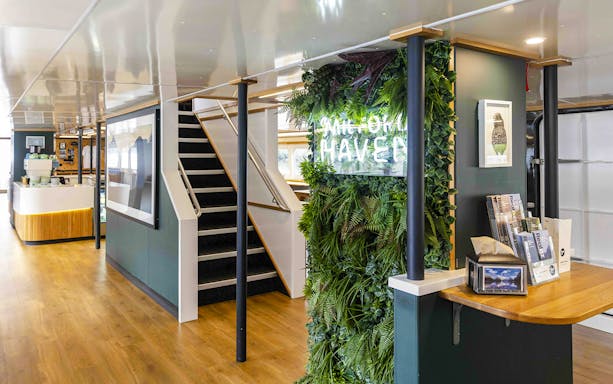 Interior of Milford Sound Haven ship with greenery wall and staircase.