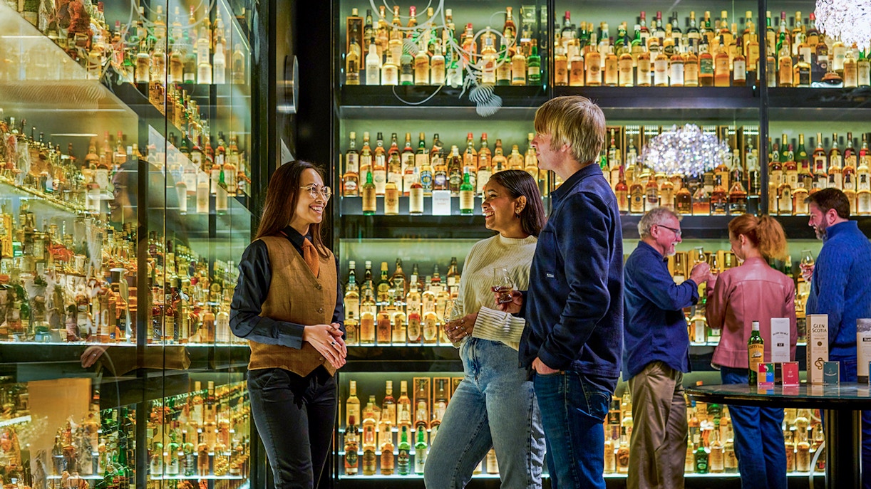 Visitors enjoying The Silver Tour at Scotch Whisky Experience, surrounded by whisky bottles.
