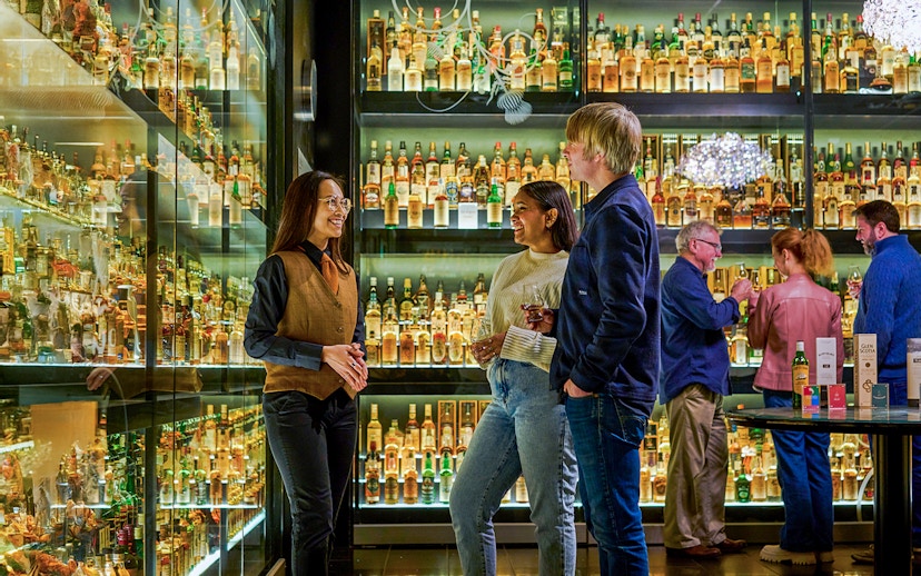 Visitors enjoying The Silver Tour at Scotch Whisky Experience, surrounded by whisky bottles.