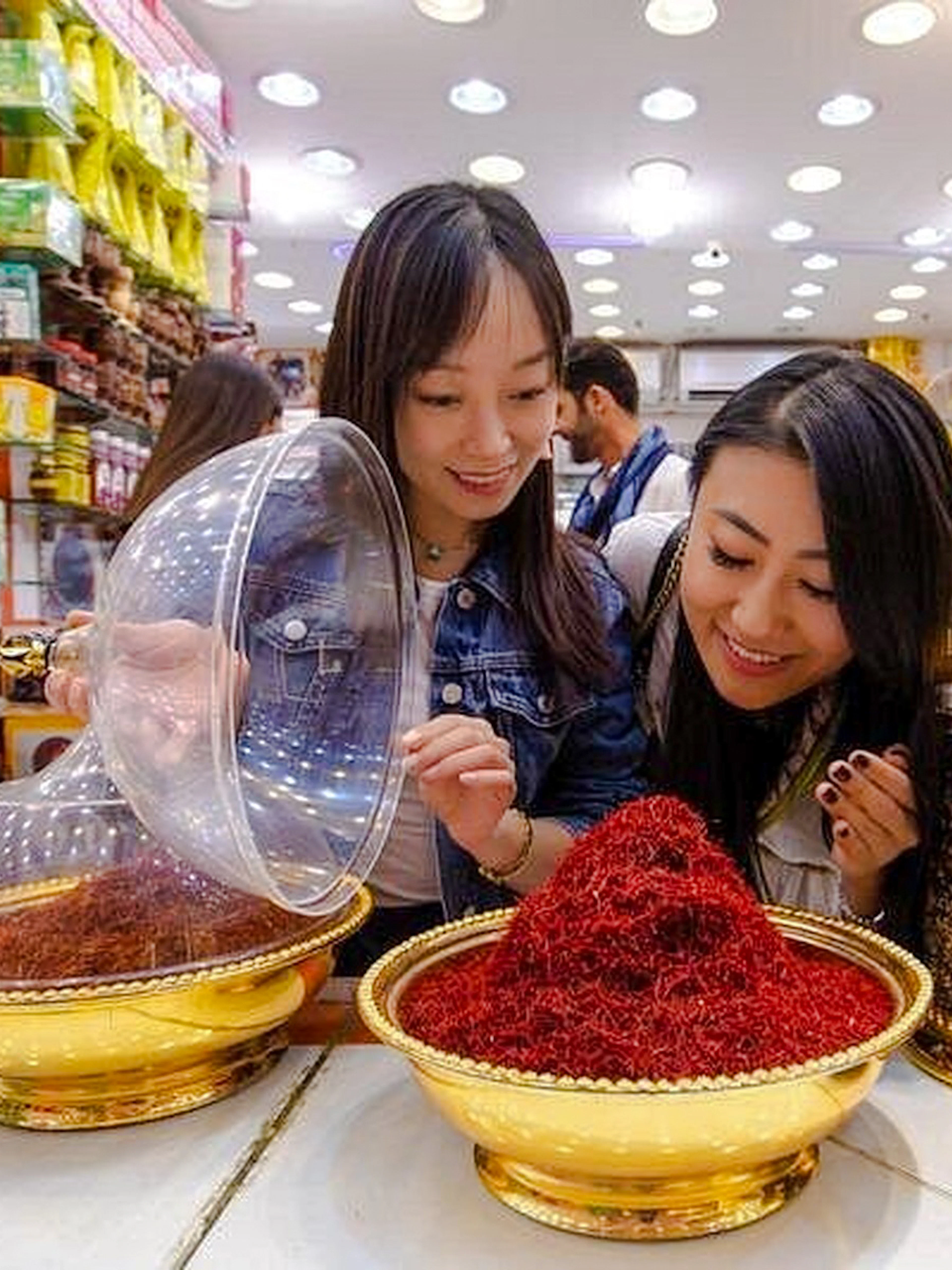 Women exploring spice shop during Old Dubai Souks walking tour.