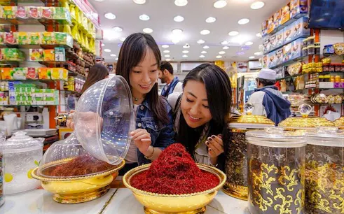 Women exploring spice shop during Old Dubai Souks walking tour.