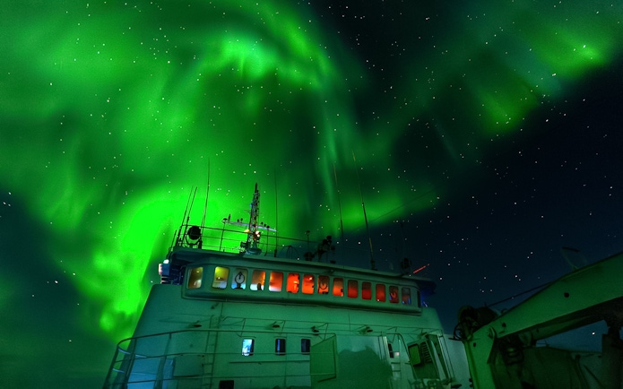 Cruise ship under Northern Lights in Reykjavik night sky.