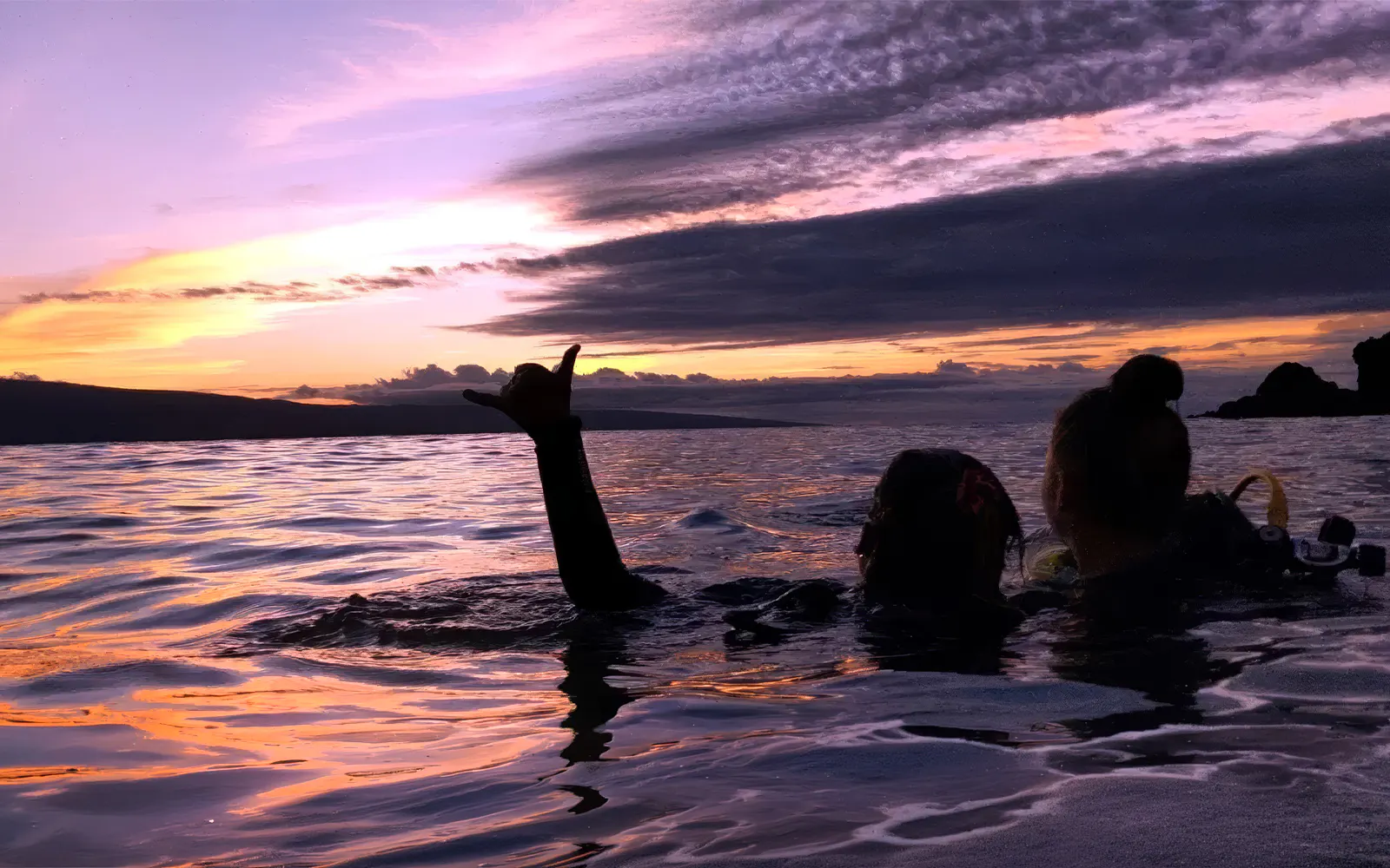 Divers in Maui waters at sunset during a night dive tour.