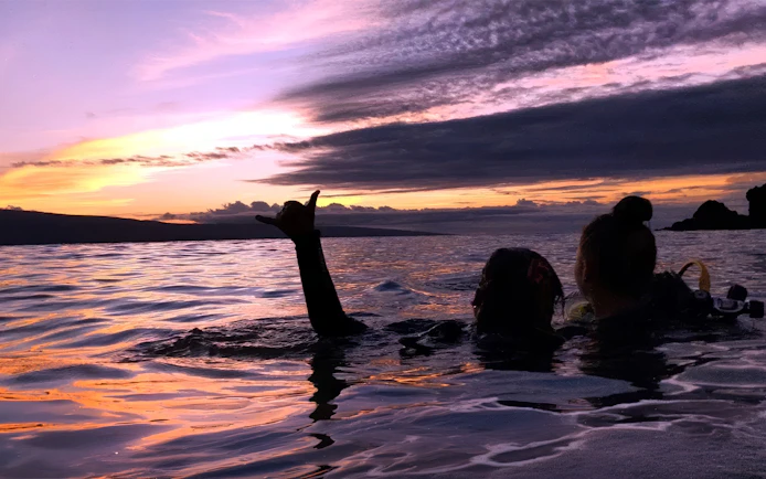 Divers in Maui waters at sunset during a night dive tour.
