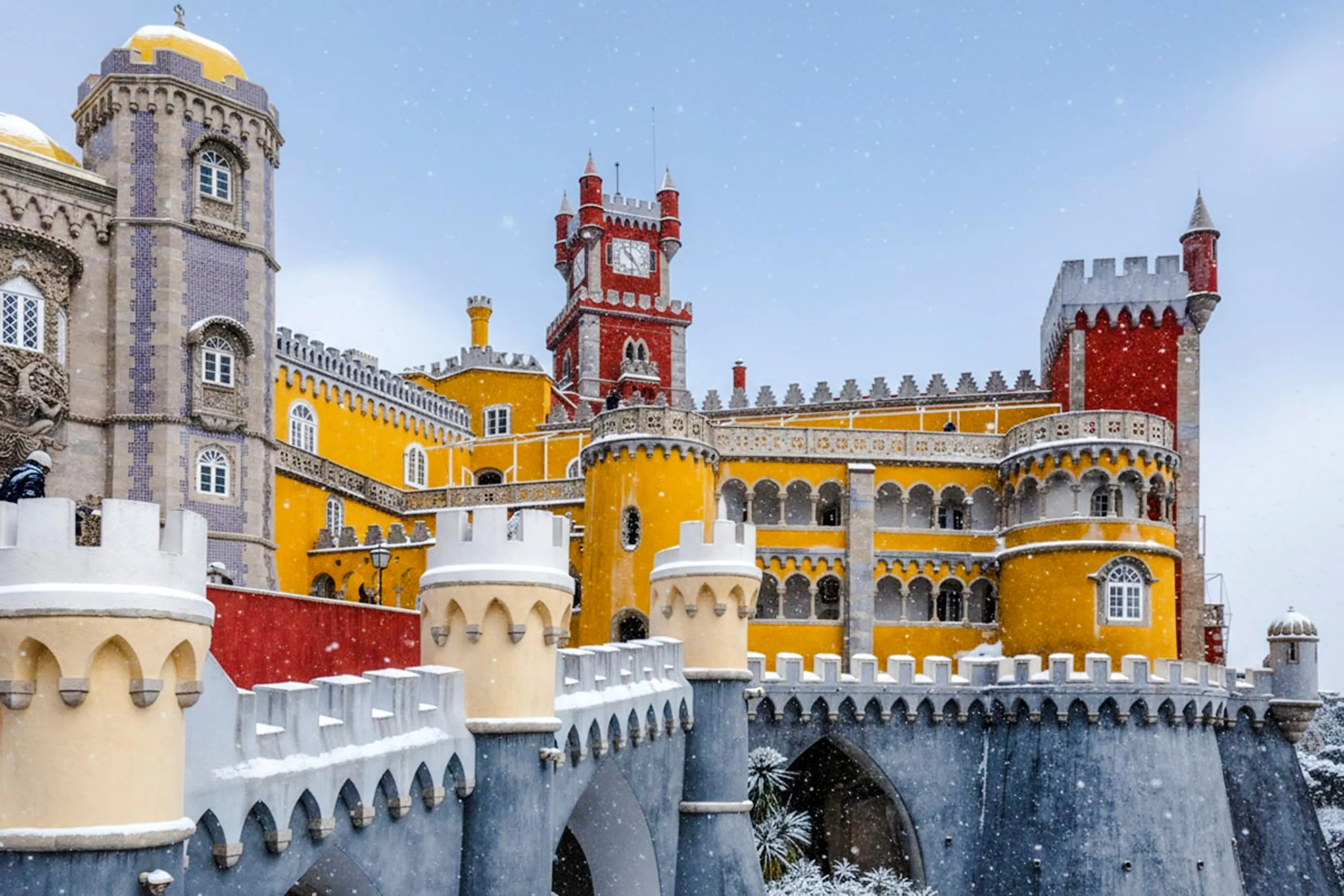 Pena Palace in Sintra with colorful towers and snow falling.
