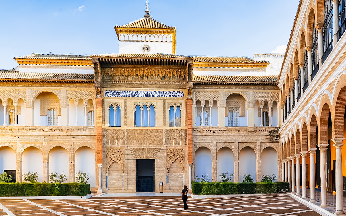 Alcazar of Seville courtyard with intricate arches and detailed facade.