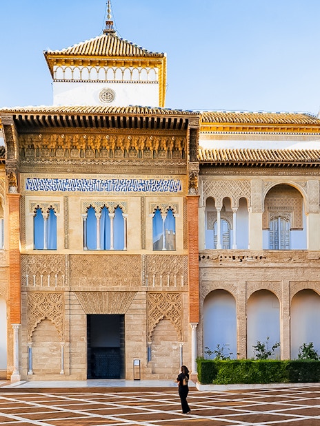 Alcazar of Seville courtyard with intricate arches and detailed facade.