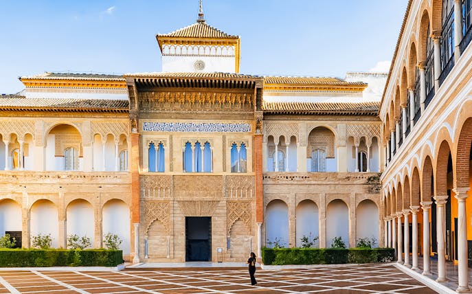 Alcazar of Seville courtyard with intricate arches and detailed facade.
