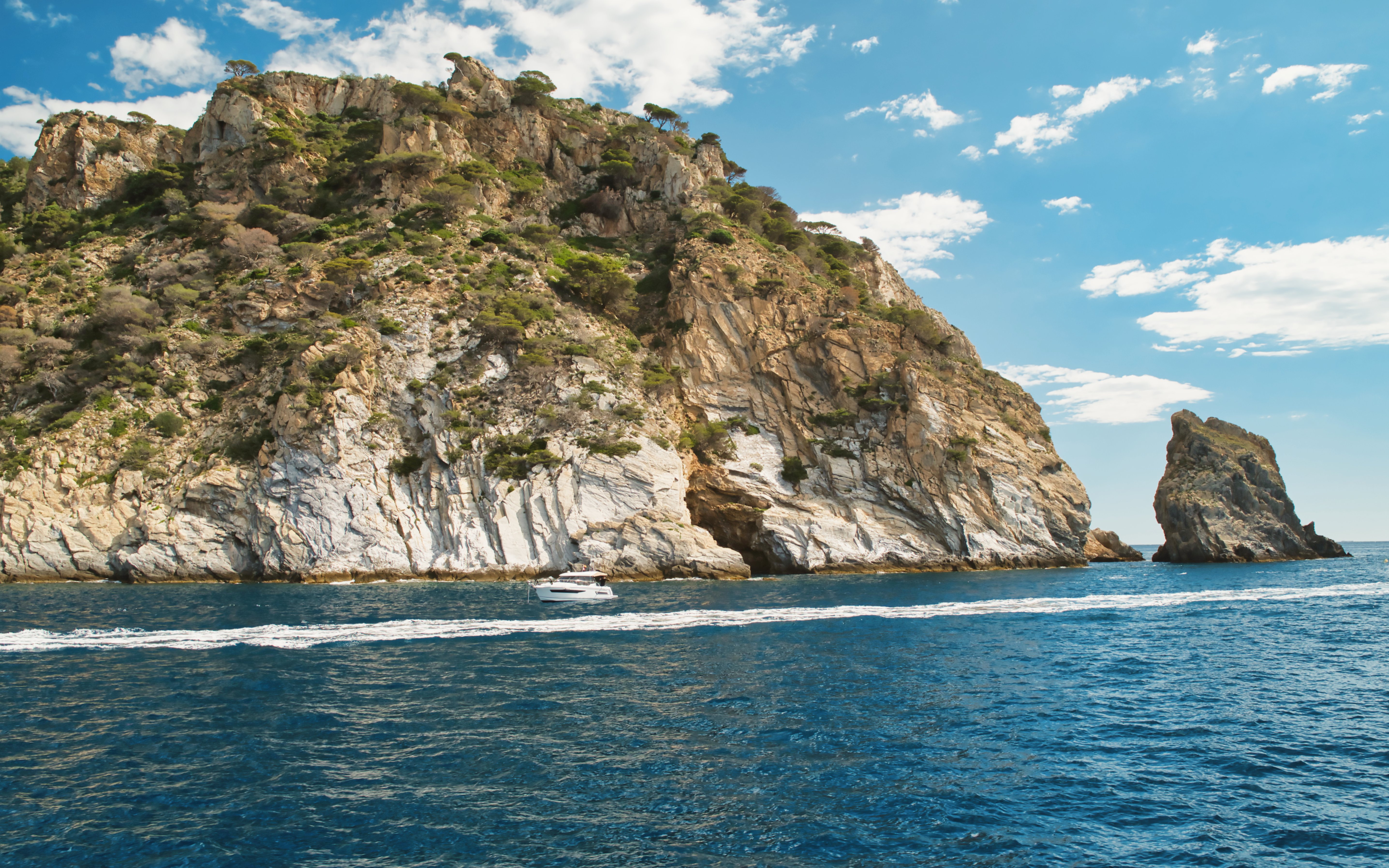 Boat near cliffs of Cap de Creus Natural Park, Mediterranean Sea, Roses, Costa Brava, Spain.