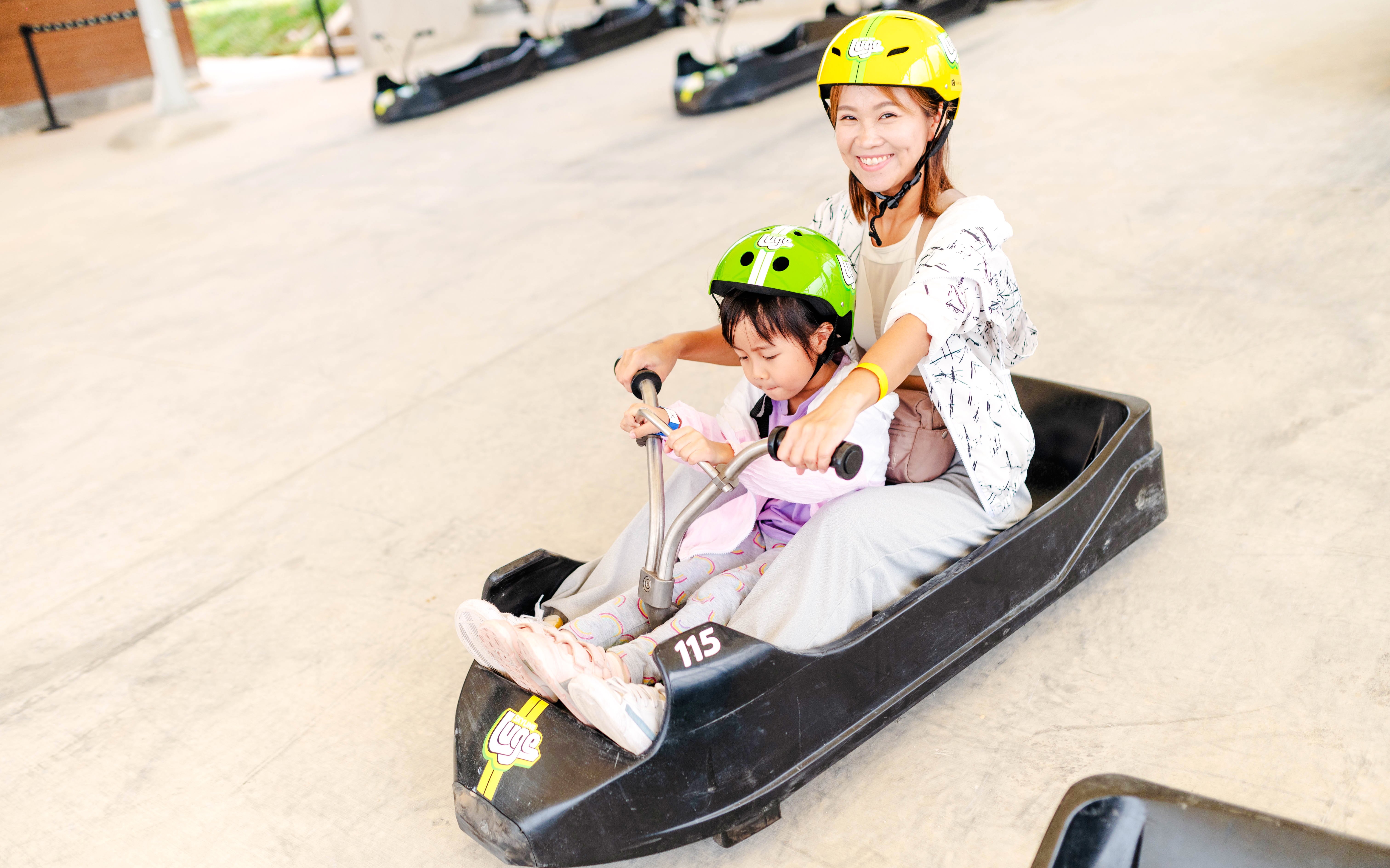 Mother and child riding a luge cart at Skyline Luge attraction.