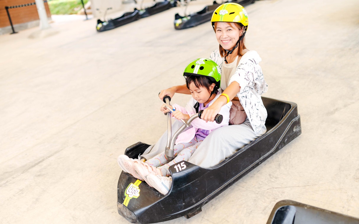 Mother and child riding a luge cart at Skyline Luge attraction.