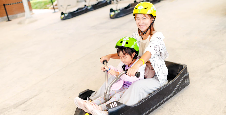 Mother and child riding a luge cart at Skyline Luge attraction.