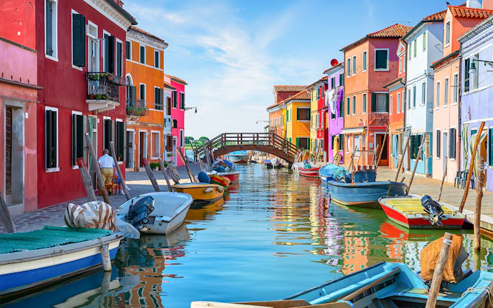 Colorful houses and boats along the canal near Tre Ponti Bridge, Burano island, Venice.