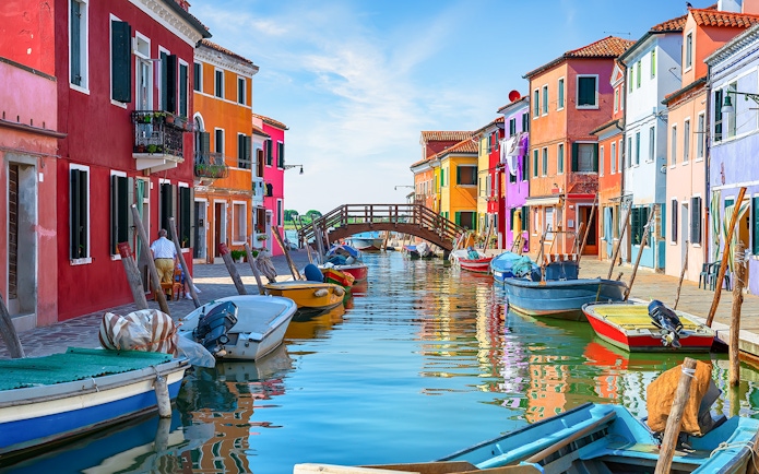 Colorful houses and boats along the canal near Tre Ponti Bridge, Burano island, Venice.