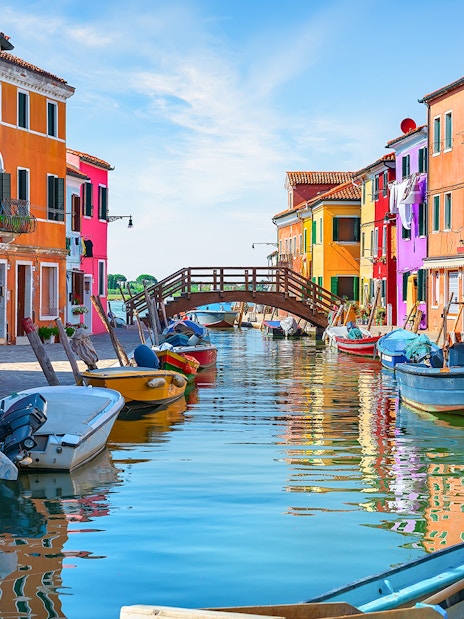 Colorful houses and boats along the canal near Tre Ponti Bridge, Burano island, Venice.